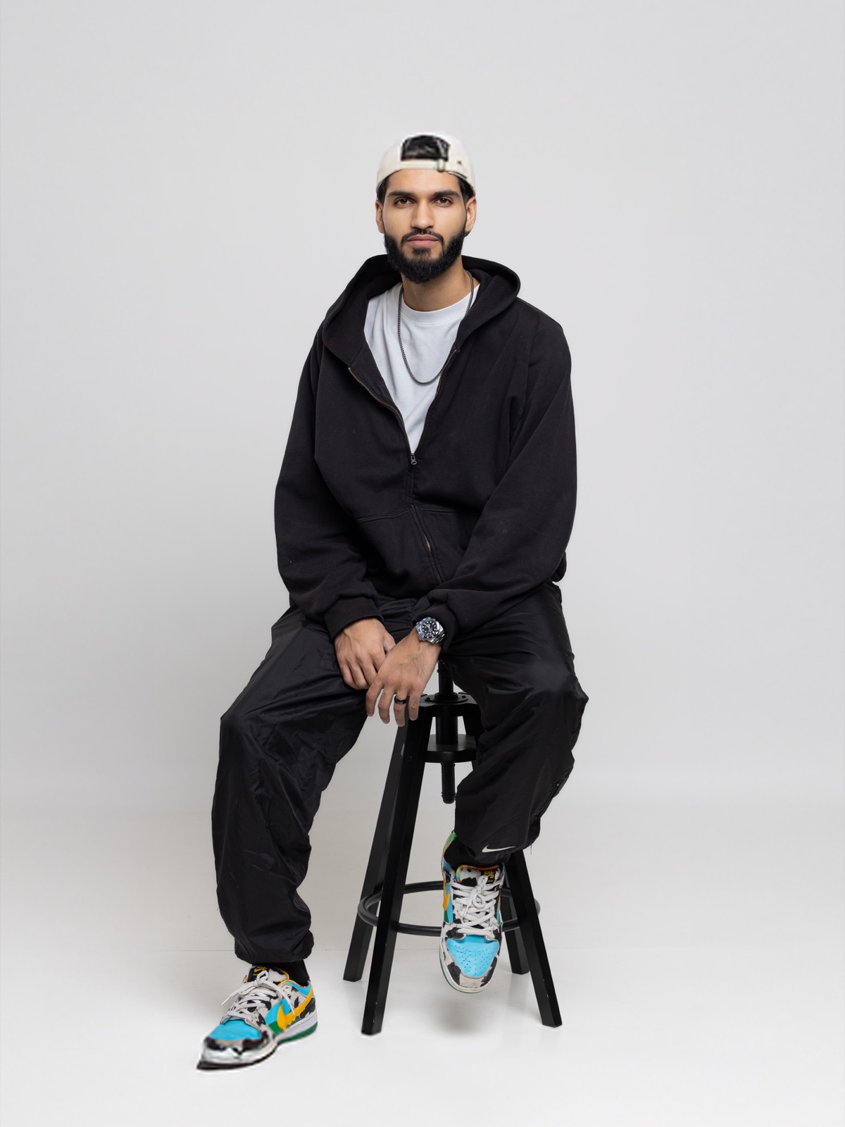 Sarfaraaz, the person behind Scents with Sarf and DecantMe, sitting on a stool